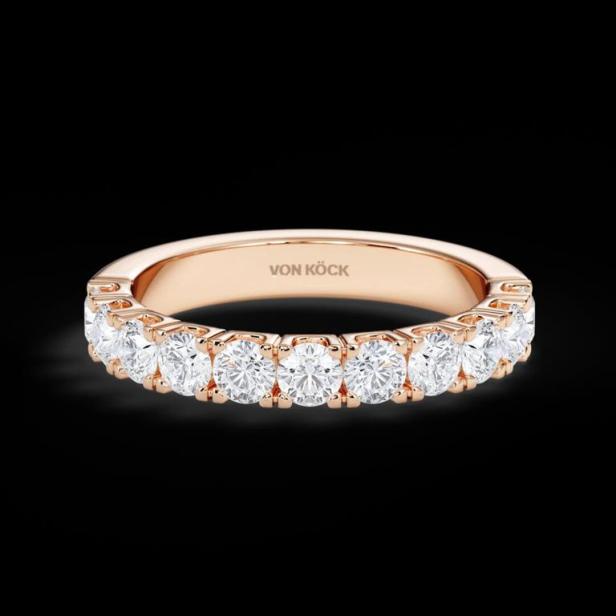 Ein goldener Ring der Marke Von Köck mit mehreren Diamanten auf einem schwarzen Hintergrund.