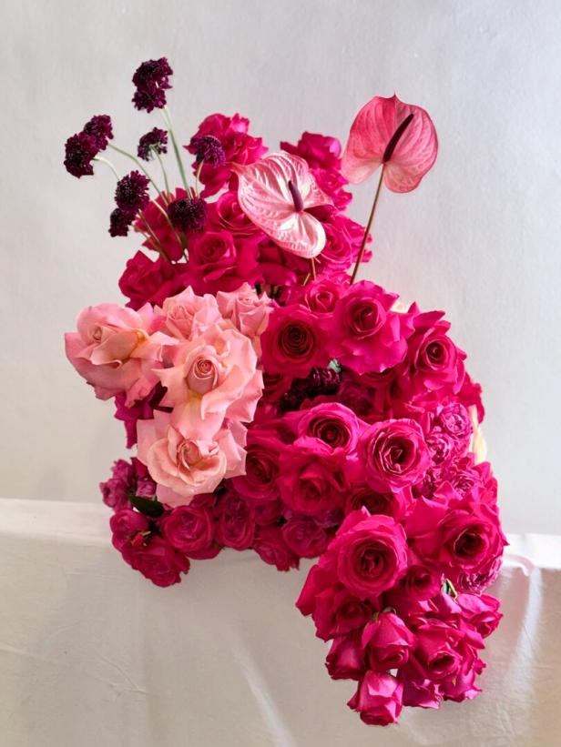 Ein Arrangement aus rosa Rosen und einer rosa Anthurie vor einem weißen Hintergrund.