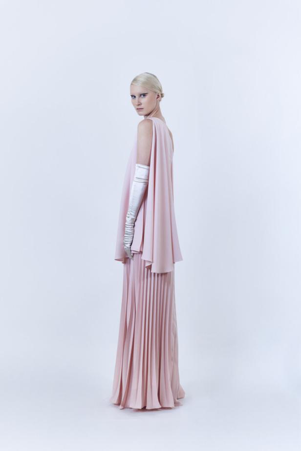 Eine Frau mit blonden Haaren trägt ein rosa Kleid und lange, weiße Handschuhe.