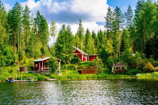 Traditonelles finnisches Holzhaus mit Sauna am See, im Hintergrund Wald