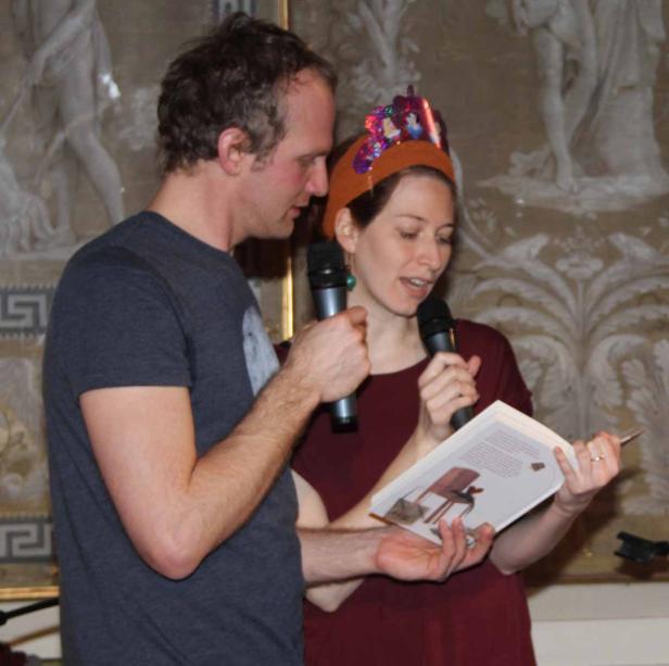 Ein Mann und eine Frau lesen mit Mikrofonen aus einem Buch vor.