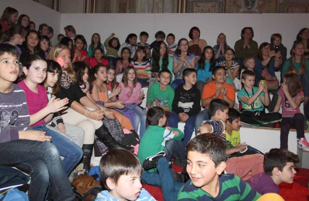 Eine Gruppe von Kindern sitzt auf einer Treppe und klatscht Beifall.