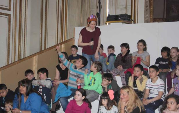 Eine Frau mit Mikrofon steht vor einer Gruppe von Kindern.