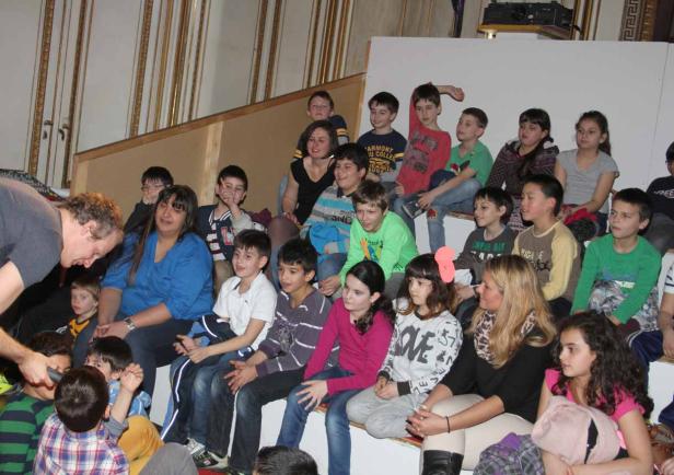 Eine Gruppe von Kindern und Erwachsenen sitzt auf einer Treppe.