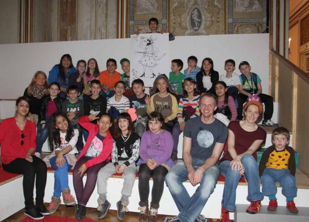 Eine Gruppe von Kindern und Erwachsenen posiert für ein Gruppenfoto mit einer Zeichnung.