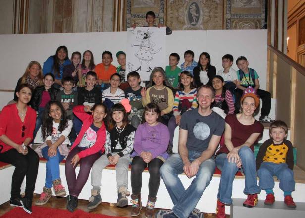 Eine Gruppe von Kindern und Erwachsenen sitzt auf einer Treppe und lächelt.