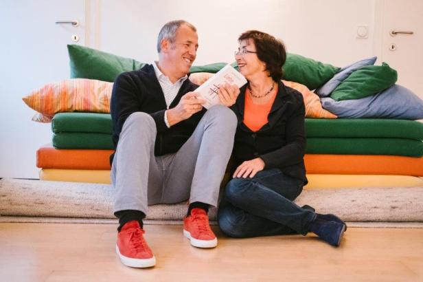 Ein Mann und eine Frau sitzen auf dem Boden und lesen gemeinsam ein Buch mit dem Titel „Liebe“.