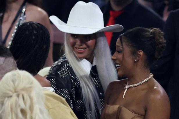 Beyoncé mit weißem Cowboyhut und silbernem Haar lächelt neben einer anderen Frau.