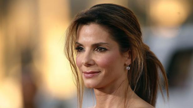 Porträt von Sandra Bullock mit zurückgebundenen Haaren und Ohrringen.