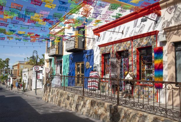 Eine farbenfrohe Straße in Mexiko mit Papel Picado-Girlanden über den Häusern.
