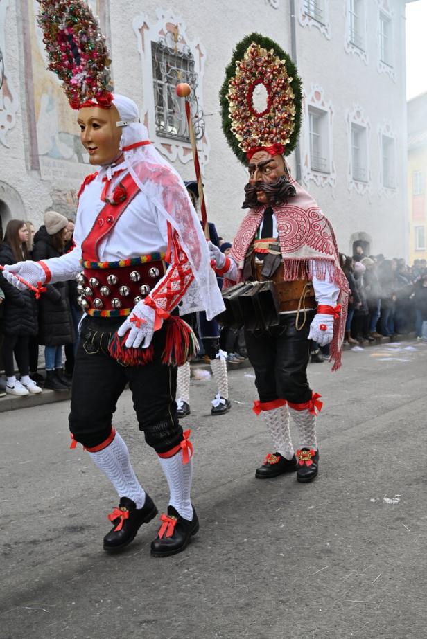 Roller und Scheller beim Schemenlaufen in Imst in Tirol auf der Straße. Männer in Kostümen mit Masken und Kopfschmuck. 