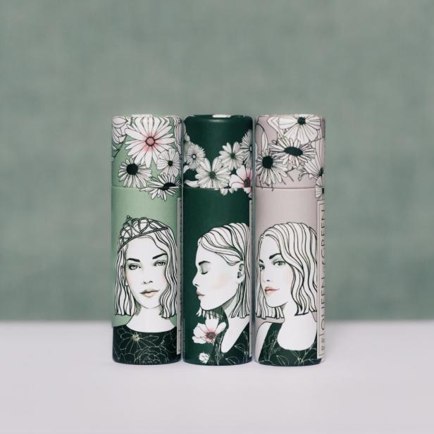 Drei Lippenpflegestifte der Marke „Queen of Green“ mit Illustrationen von Frauen und Blumen.