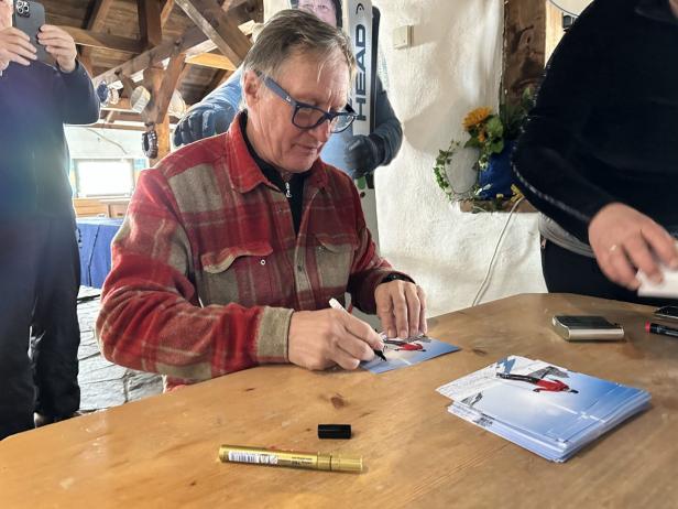 Skikaiser Franz Klammer signiert Autogrammkarten auf einer Skihütte