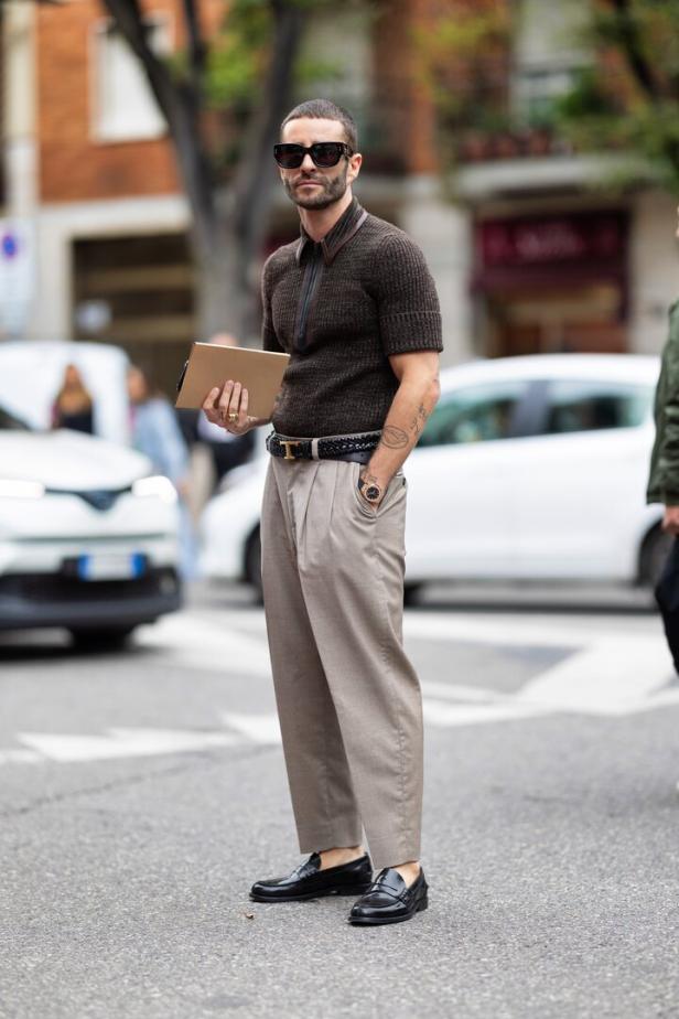 Ein Mann mit Sonnenbrille und braunem Poloshirt steht auf der Straße.
