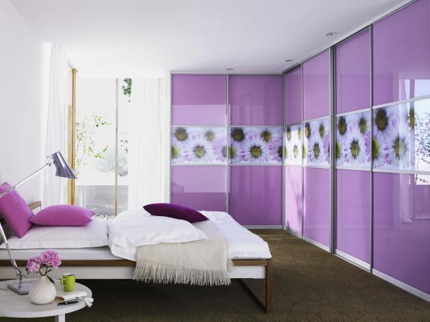 Ein Schlafzimmer mit einem Bett und einem großen Schrank mit rosa Türen und Gänseblümchenmuster.