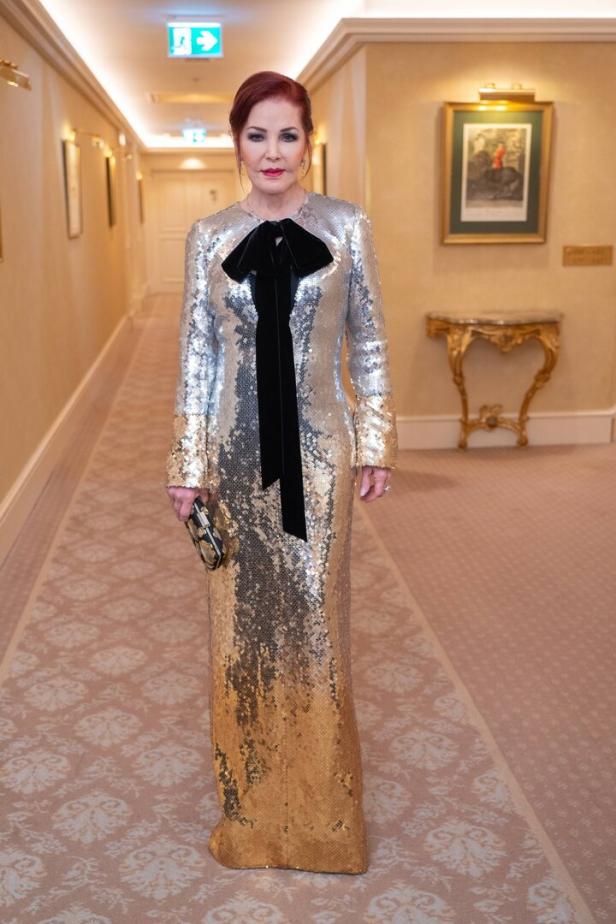 Priscilla Presley in einem silber-goldenen Paillettenkleid mit schwarzer Schleife.