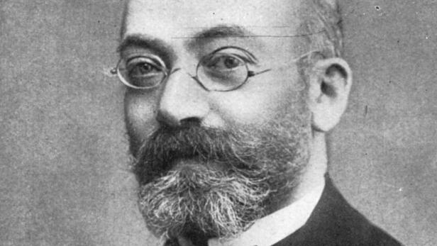 Ein Porträt eines Mannes mit Bart und runder Brille.