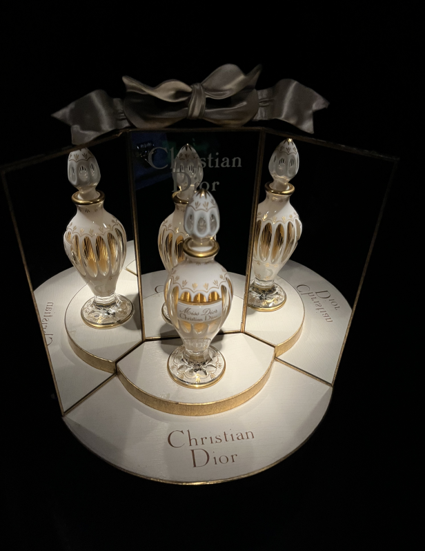 Ein Dior-Parfumflakon „Miss Dior“ in einer Vitrine mit Spiegeln und Schleife.