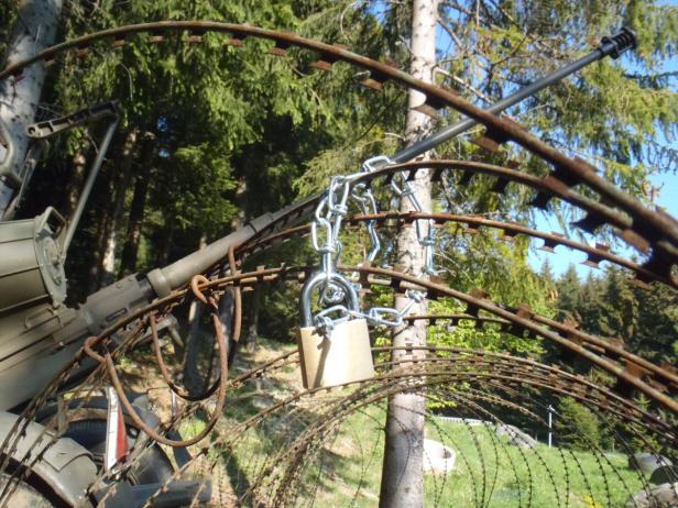 Eine Kanone ist mit Stacheldraht, einer Kette und einem Vorhängeschloss gesichert.