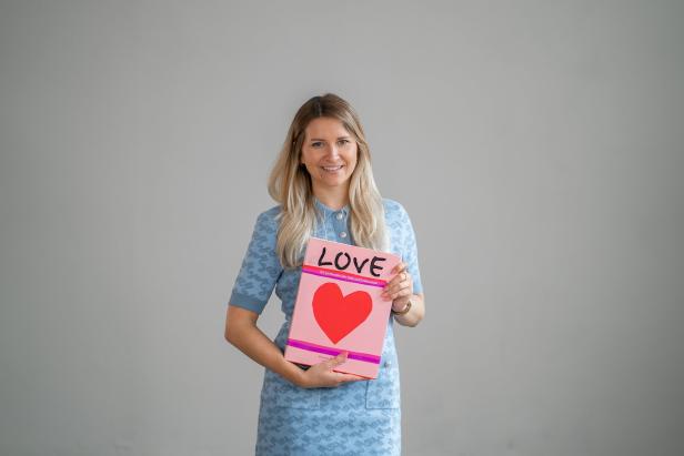 Eine Frau hält ein Buch mit der Aufschrift „Love“ und einem roten Herz in den Händen.