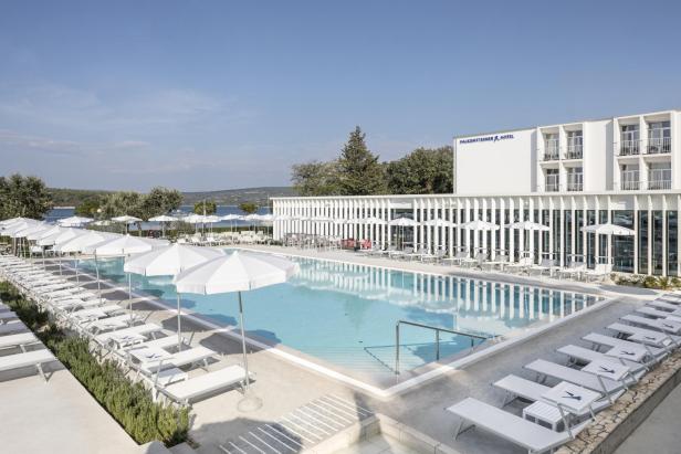 Ein Schwimmbad mit Liegestühlen und Sonnenschirmen vor dem Falkensteiner Hotel.