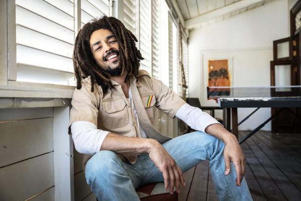 Ein lächelnder Mann mit Dreadlocks sitzt in einem hellen Raum.