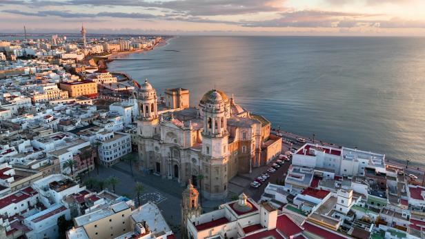 Luftaufnahme von Cádiz, Spanien, mit der Kathedrale im Vordergrund und dem Meer im Hintergrund.