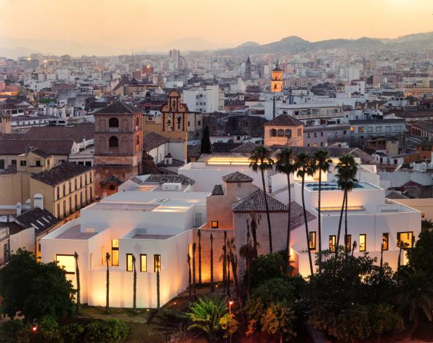 Blick auf Málaga mit weiß getünchten Gebäuden und Palmen im Abendlicht.