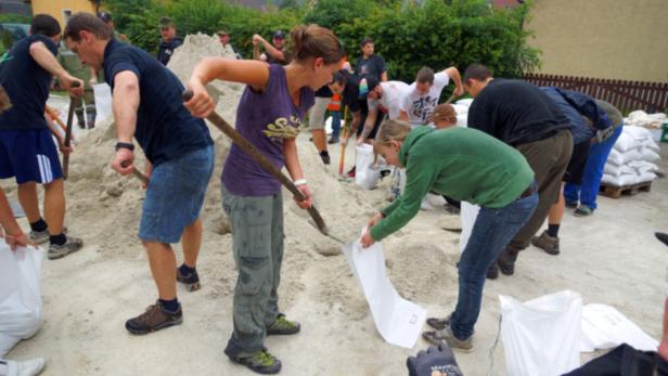 Eine Gruppe von Menschen füllt Sandsäcke zum Schutz vor Hochwasser.