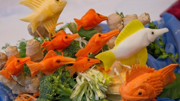 Kreative Dekoration mit geschnitzten Fischfiguren aus Gemüse und Ingwer.