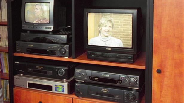 Ein Schrank voll mit alten Fernsehern und Videorekordern.