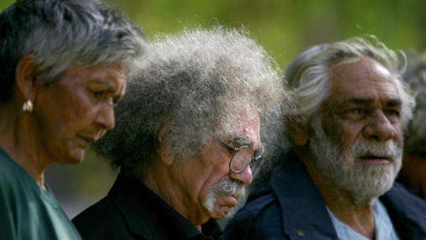 Drei ältere Menschen mit grauen Haaren stehen nebeneinander.