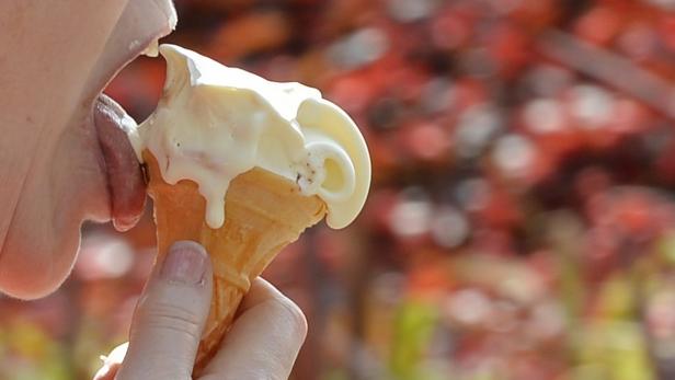 Eine Person leckt an einem tropfenden Eis in einer Waffel.