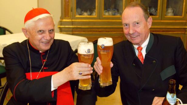 Joseph Ratzinger, später Papst Benedikt XVI., prostet mit einem Mann mit Biergläsern zu.
