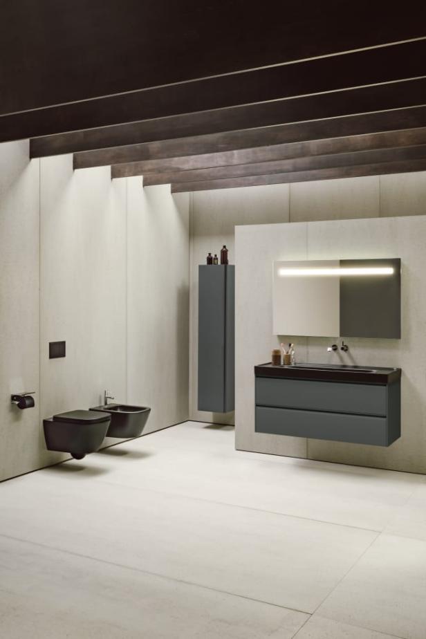 Ein modernes Badezimmer mit Toilette, Bidet, Waschtisch und beleuchtetem Spiegel.