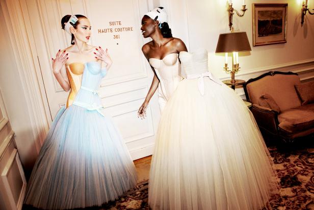 Zwei Models in Haute-Couture-Kleidern stehen vor der Tür einer Suite.