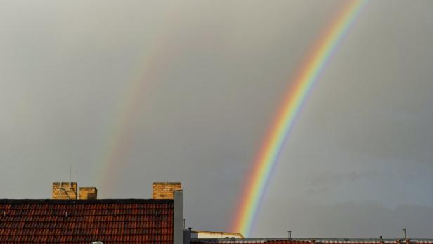 Ein doppelter Regenbogen über den Dächern eines Hauses.