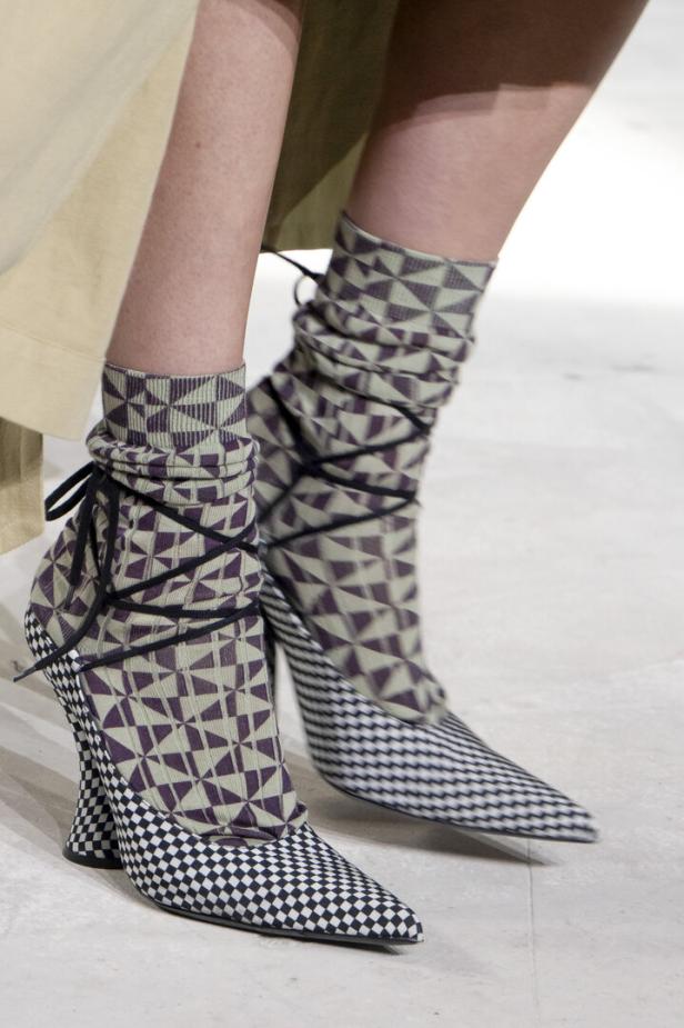 Nahaufnahme von gemusterten Schuhen und Socken mit Schnürung an den Füßen einer Person.