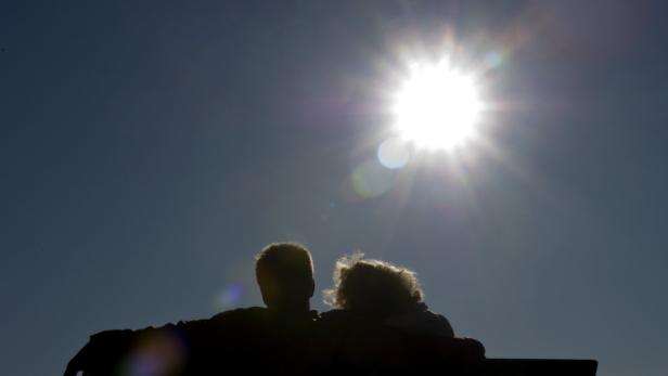 Ein Paar sitzt im Gegenlicht der Sonne auf einer Bank.