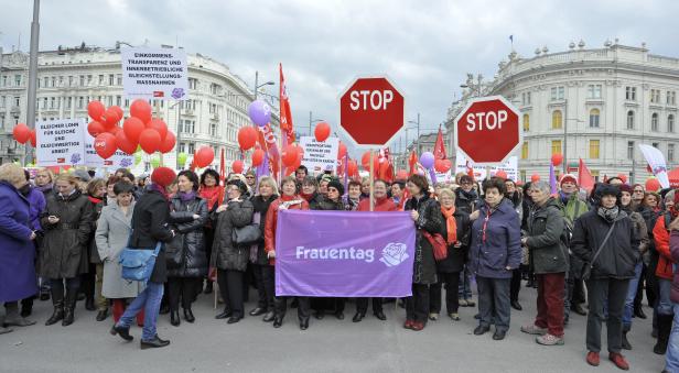 Eine Demonstration zum Frauentag mit Schildern und roten Luftballons in einer Stadt.