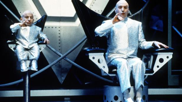 Dr. Evil und Mini-Me sitzen in glitzernden Anzügen auf ihren Stühlen.