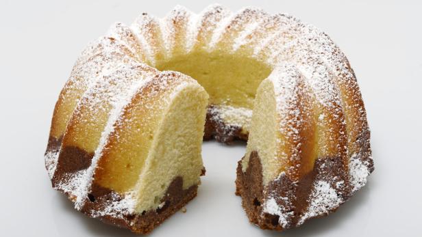 Ein angeschnittener Marmorkuchen mit Puderzucker bestreut.