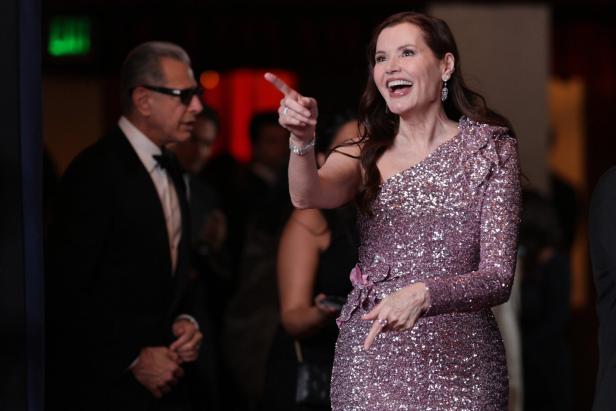 Geena Davis in einem glitzernden Kleid auf einer Veranstaltung, auf etwas zeigend.