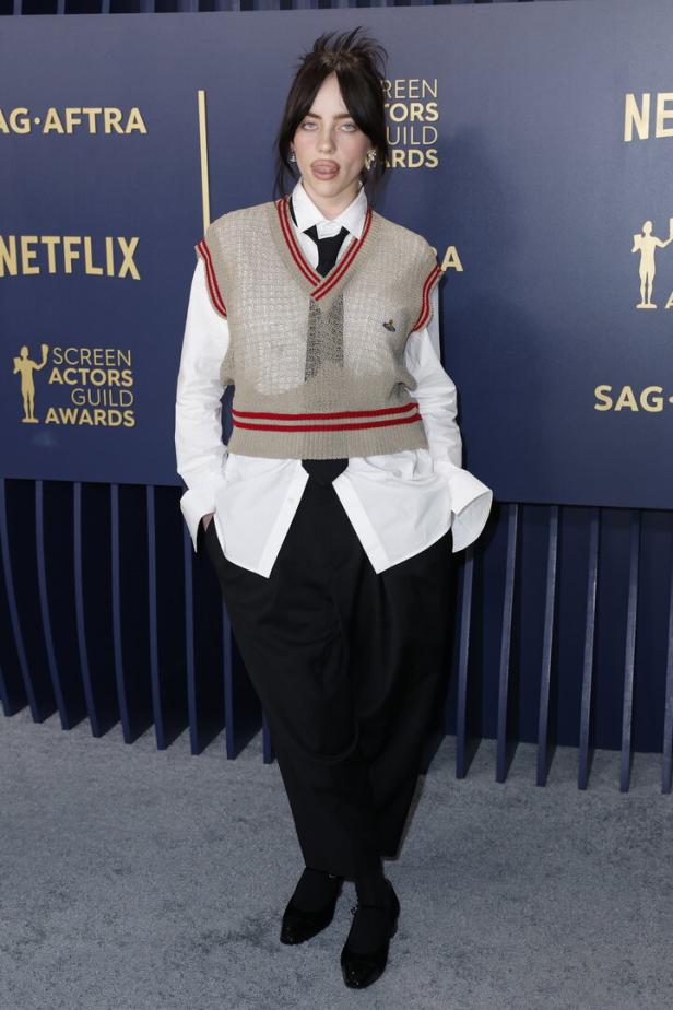 Billie Eilish posiert auf dem roten Teppich mit herausgestreckter Zunge.