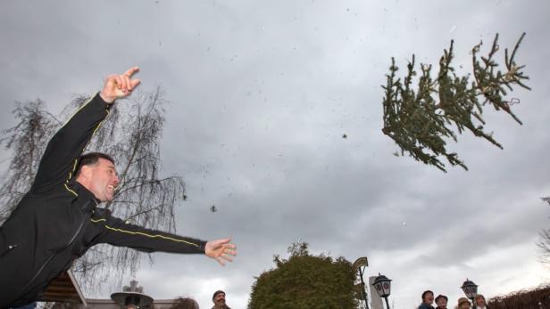 Ein Mann wirft einen Weihnachtsbaum in den Himmel.