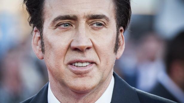 Ein Porträt von Nicolas Cage auf einem roten Teppich.