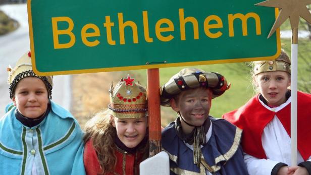 Kinder, als die Heiligen Drei Könige verkleidet, stehen unter einem Schild mit der Aufschrift „Bethlehem“.