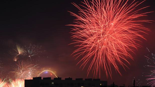 Ein Feuerwerk erhellt den Nachthimmel über einer Stadt.