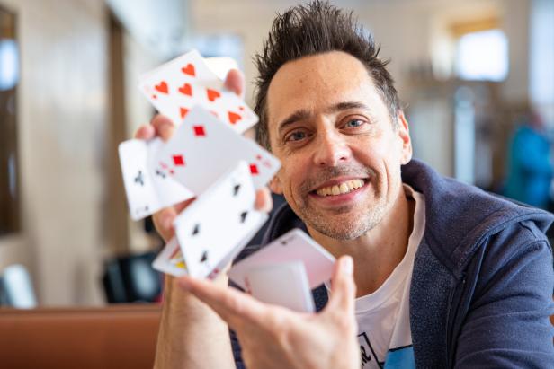 Ein lächelnder Mann hält Spielkarten in der Hand.