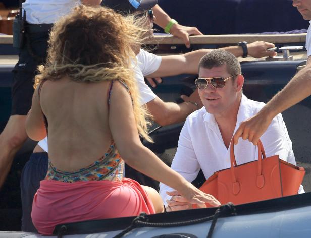 Ein Mann mit Sonnenbrille und Hemd hält eine orangefarbene Handtasche auf einem Boot.